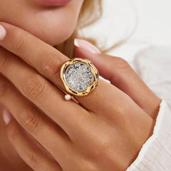 Close-up of a hand wearing the Ring Coiné, featuring a gold coin design with a pearl accent.
