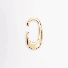 Earcuff Clip in brass with a sleek, polished curve, showcasing minimalist design and fluid strength.