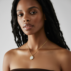 Model wearing Necklace Coiné, a gold-plated brass necklace with intricate coin pendant design.