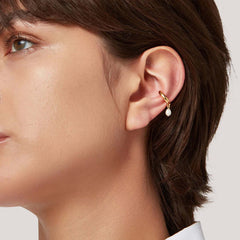 Earcuff Drop featuring a brass, gold-plated design with a suspended freshwater pearl on the upper ear.
