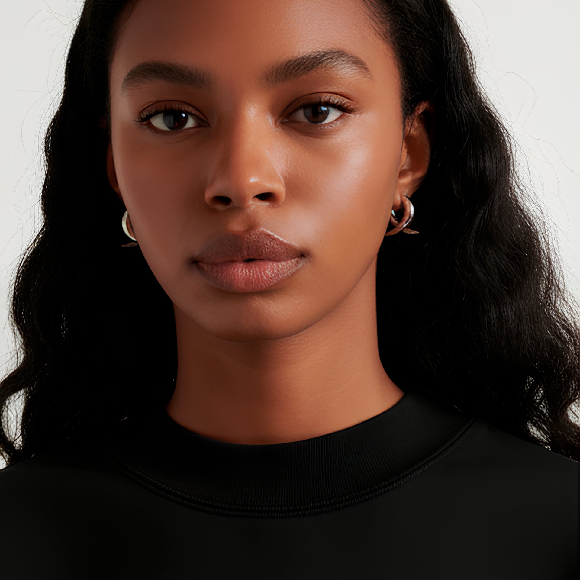 Close-up of a model wearing Earrings Flux, showcasing their elegant brass and platinum design.