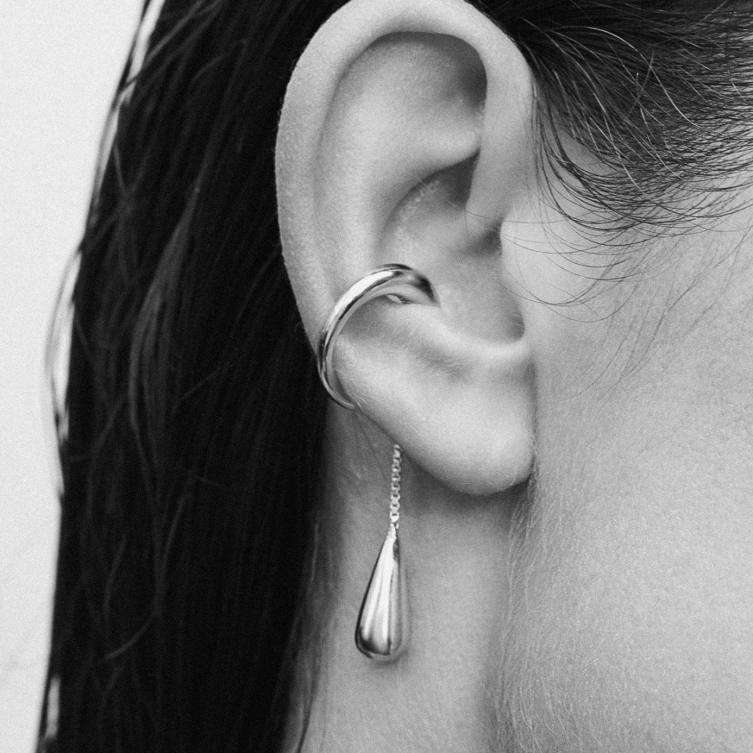 Earcuff Dew in silver style, showcasing a smooth droplet design elegantly hanging from the ear.