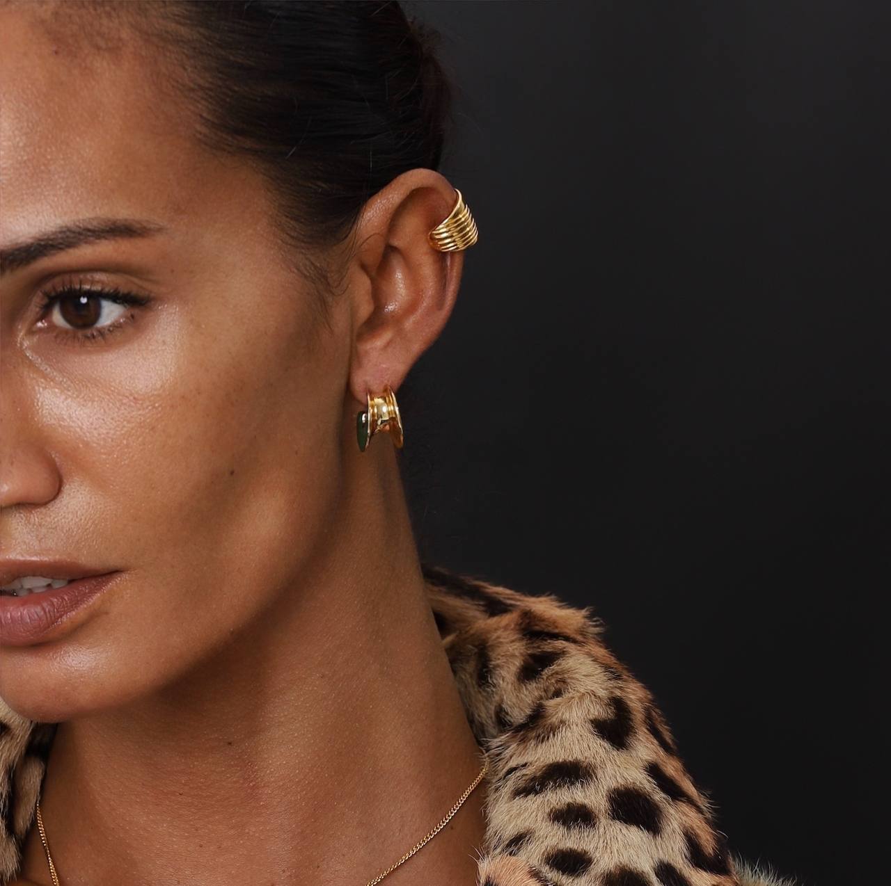 Elegant model showcasing Earcuff Stria in gold plating, complemented by a stylish leopard print coat.