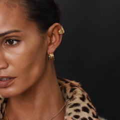 Elegant model showcasing Earcuff Stria in gold plating, complemented by a stylish leopard print coat.