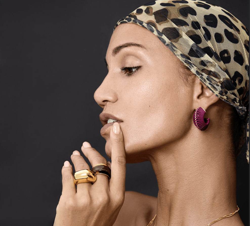 Model showcasing Earrings Arc with golden accents and textured surface, complemented by rings and a leopard-print headscarf.