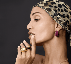Model showcasing Earrings Arc with golden accents and textured surface, complemented by rings and a leopard-print headscarf.
