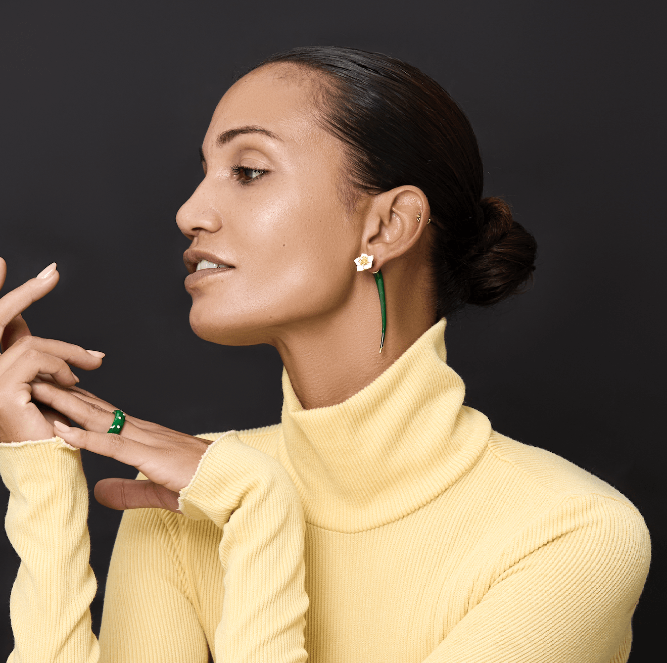 Earrings Iris showcasing delicate flower design in gold-plated brass, featured on a model in a yellow turtleneck.