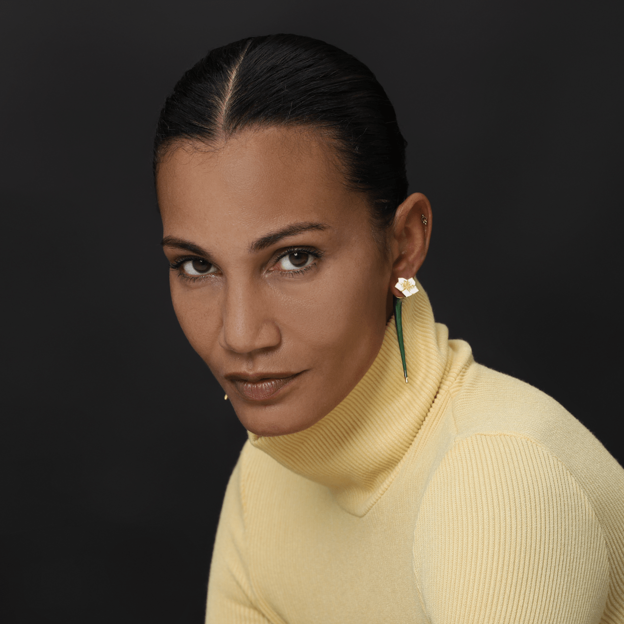 Earrings Iris worn by a woman in a yellow turtleneck, highlighting their floral design and elegant charm.