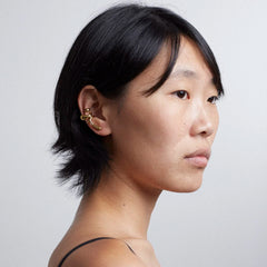 Model showcasing the Earcuff Lilt, a brass, gold-plated ear accessory with elegant curves.