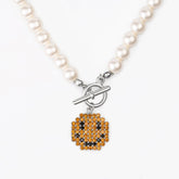 Necklace Smile featuring brass, pearl, platinum plating, and a playful zircon inlay charm.