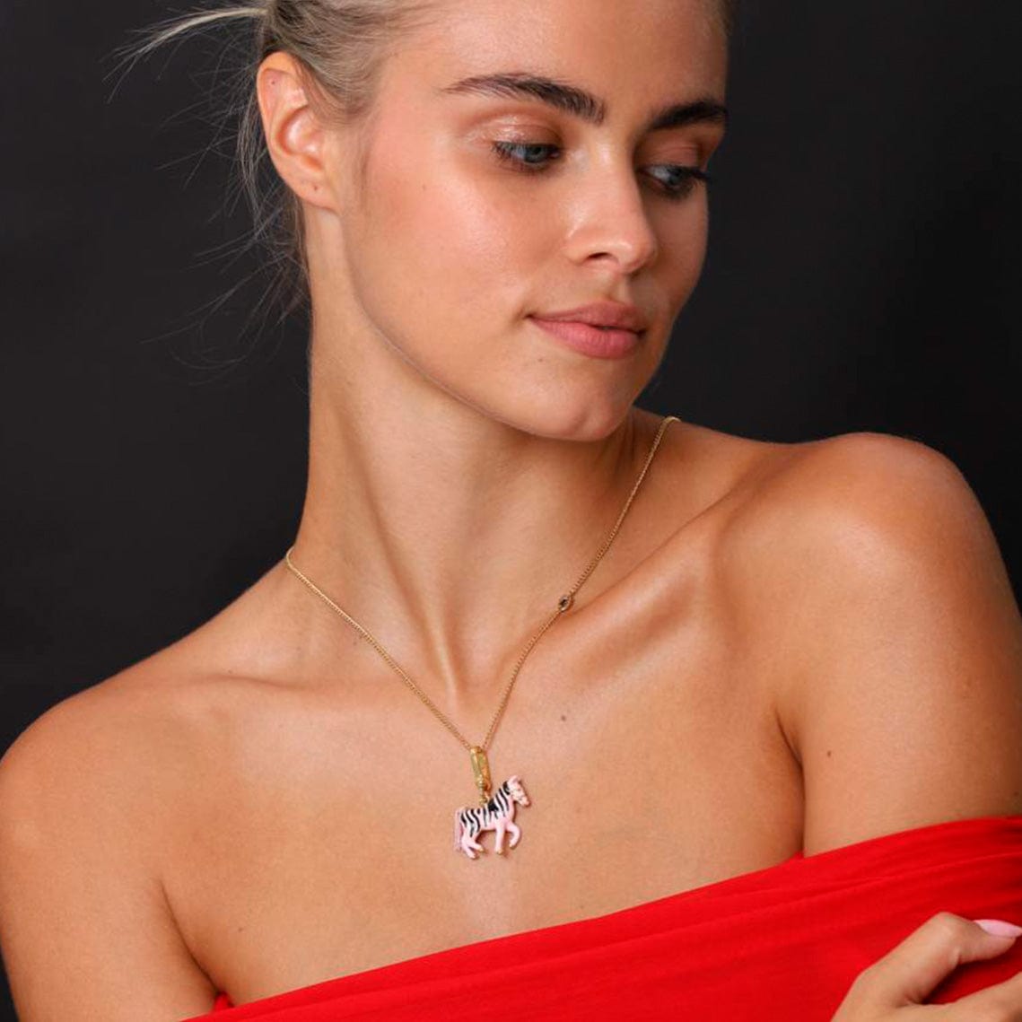 A woman wearing a playful Necklace Zebra in pink and gold, showcasing its whimsical design and vibrant style.