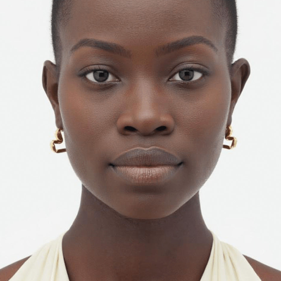 Close-up of model wearing the Earrings Sway, featuring brass and gold-plated design with elegant curves.