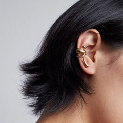 Earcuff Lilt showcasing a gold-plated design, elegantly worn on a model's ear, highlighting organic curves.