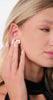 Close-up of model wearing Earrings Iris, stylish gold-plated flower earrings with white blossom and green stems.