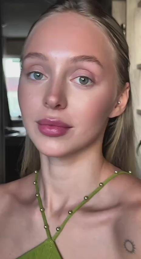 Model showcasing modern style with a natural makeup look and a green top, exuding effortless beauty and grace.