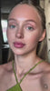 Model showcasing modern style with a natural makeup look and a green top, exuding effortless beauty and grace.
