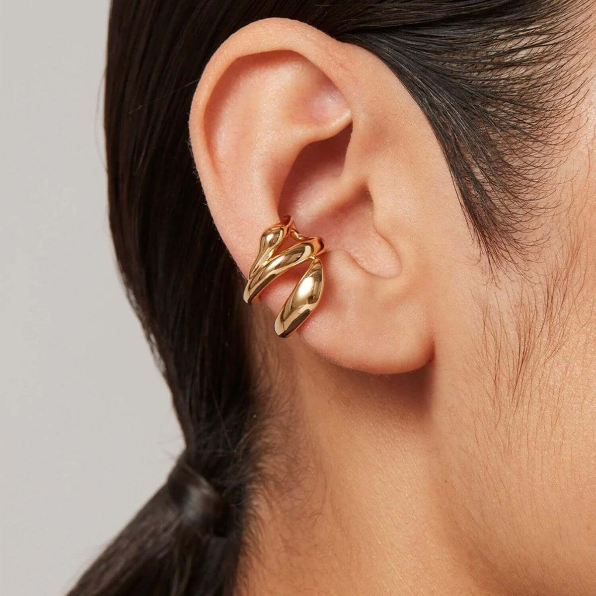 Close-up of Earcuff Flow showcasing its sculptural gold design wrapped around the ear cartilage.